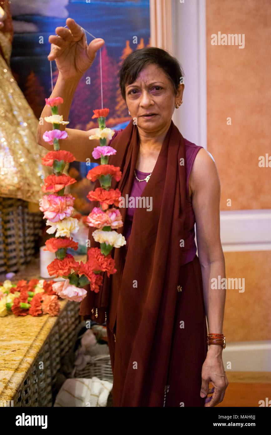 Portrait d'un adorateur à un temple hindou qui coud fleurs ensemble pour être utilisé dans un dimanche matin de prière. Je Richmond Hill Queens, NYC Banque D'Images
