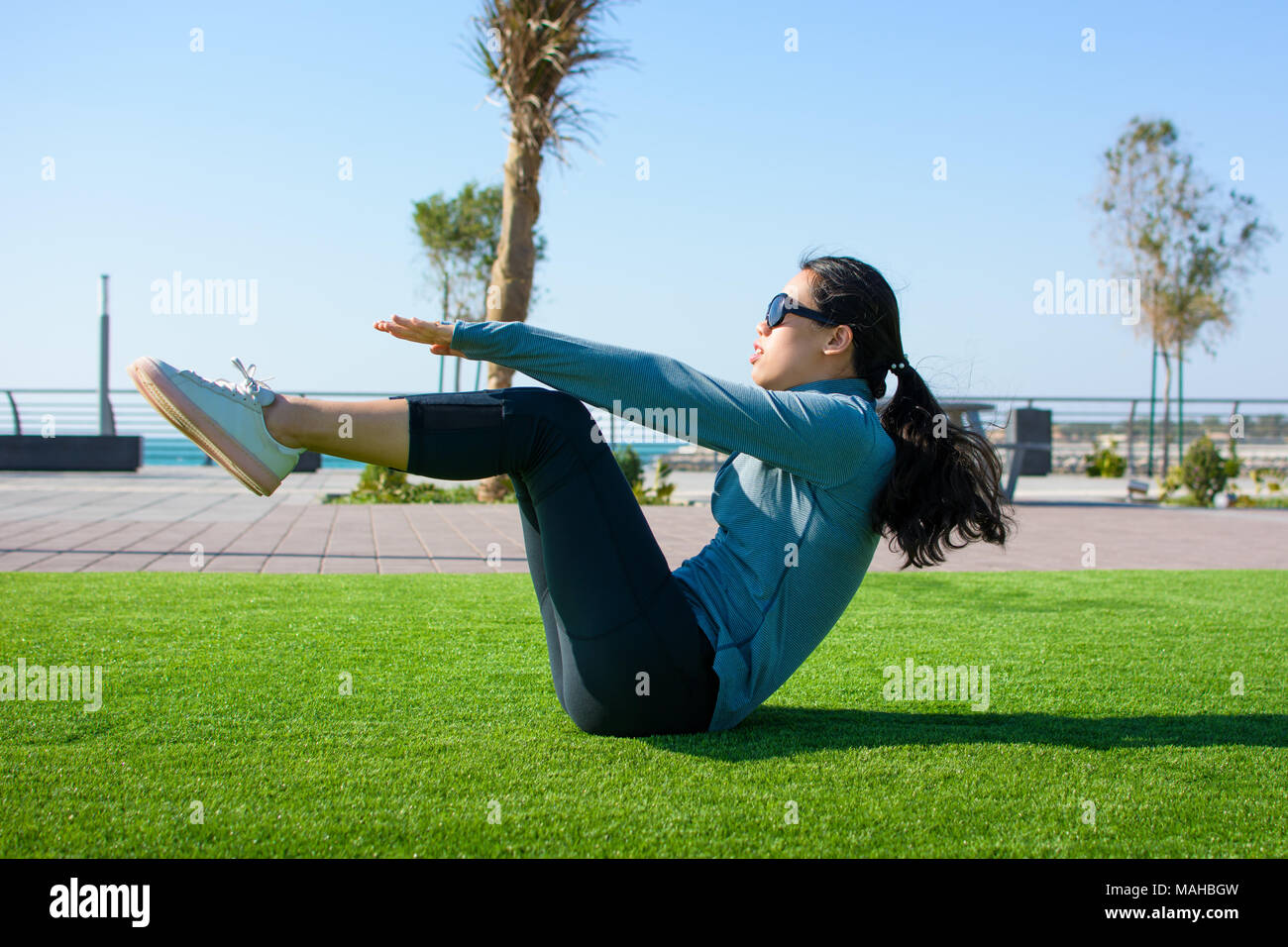 Girl doing abdominaux sur l'herbe, d'entraînement en plein air Banque D'Images
