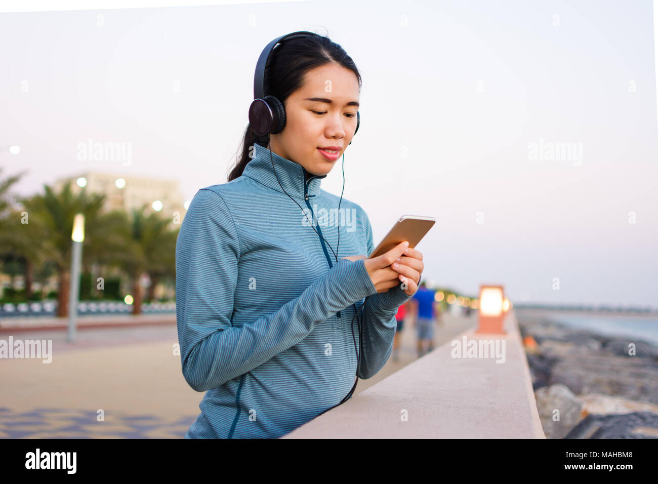 Girl en utilisant le téléphone et écouter de la musique avec des écouteurs sur la promenade Banque D'Images