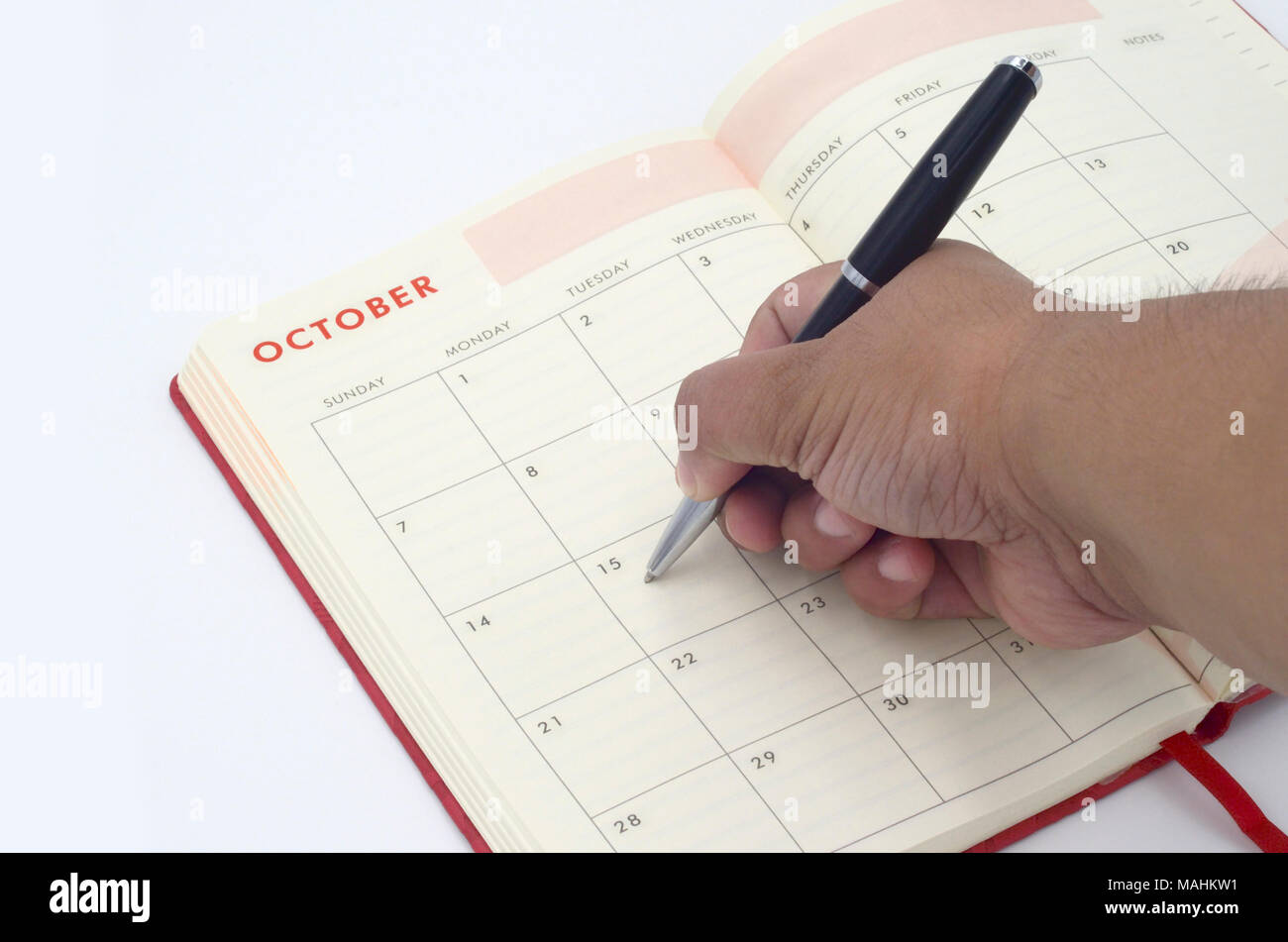 une main écrivant une entrée sur le calendrier ou le planificateur Banque D'Images