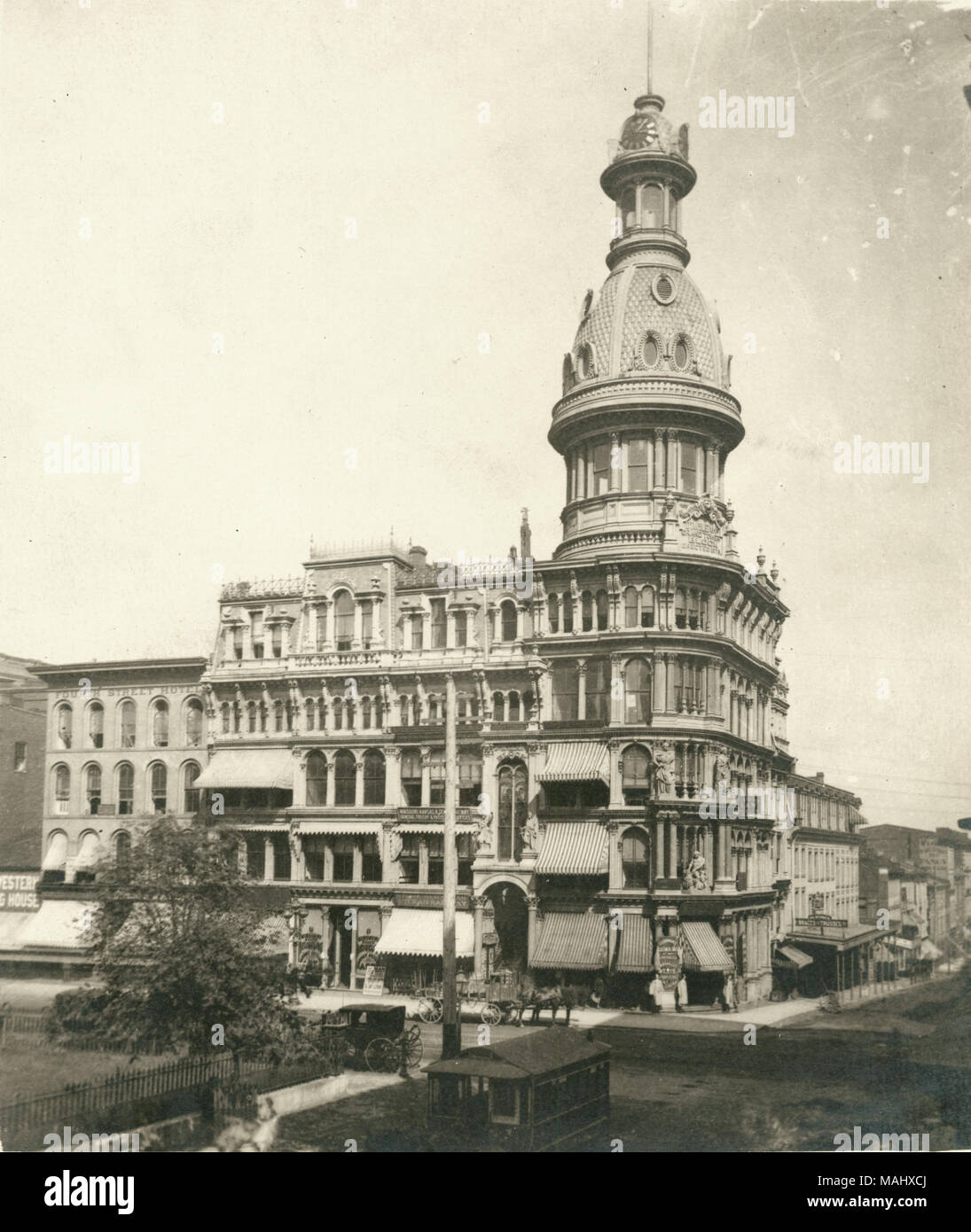 Photographie d'un grand bâtiment avec des colonnes, des auvents, et une partie d'un dôme. Il y a plusieurs véhicules tirés par des chevaux dans la rue autour de l'immeuble. Titre : McLean, angle nord-est de quatrième et Market Streets. . 1876. Emil Boehl Banque D'Images