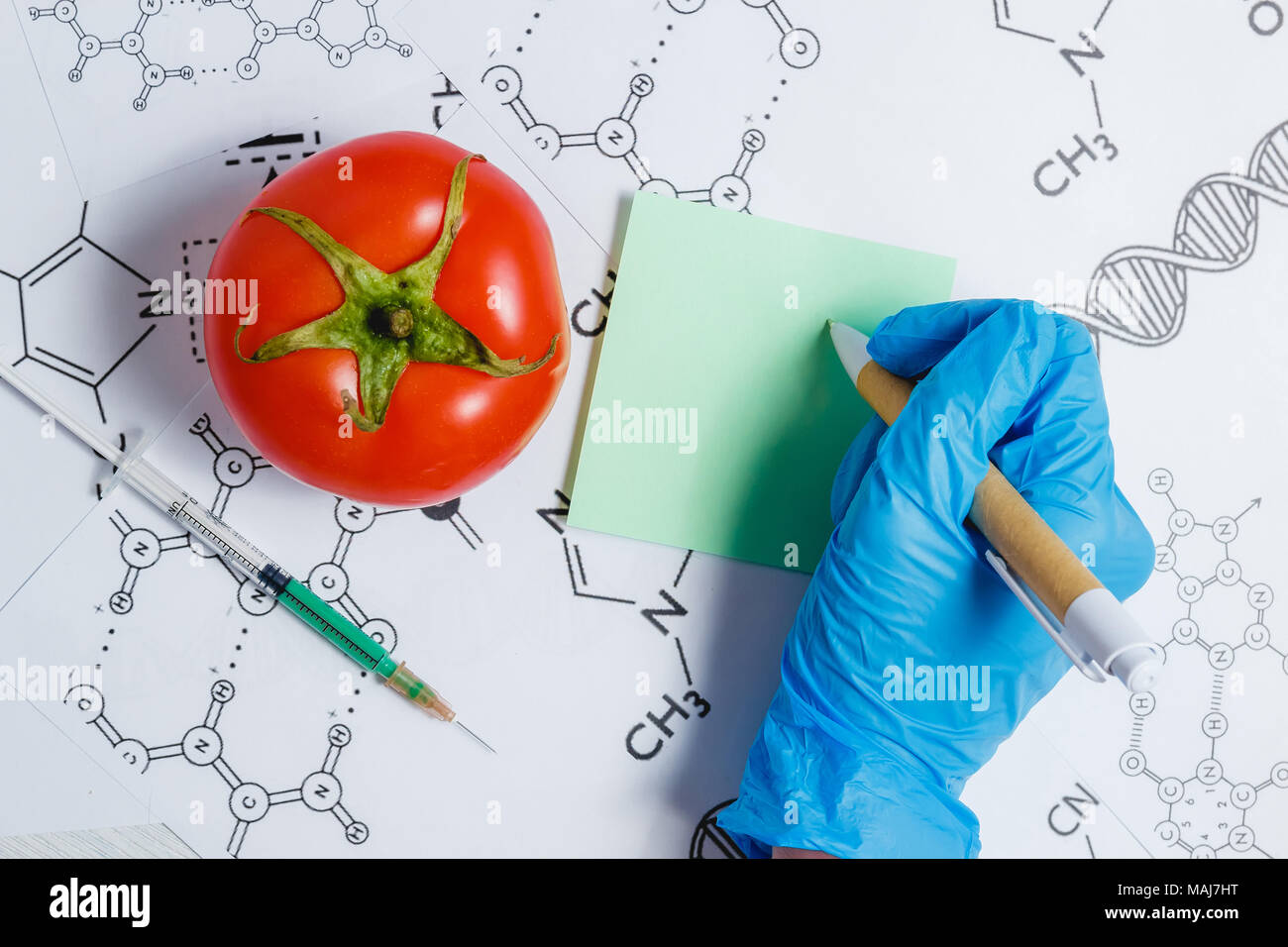Notez scientifique OGM, un liquide vert dans la seringue, Rouge tomate - Genetically Modified Food Concept. Banque D'Images