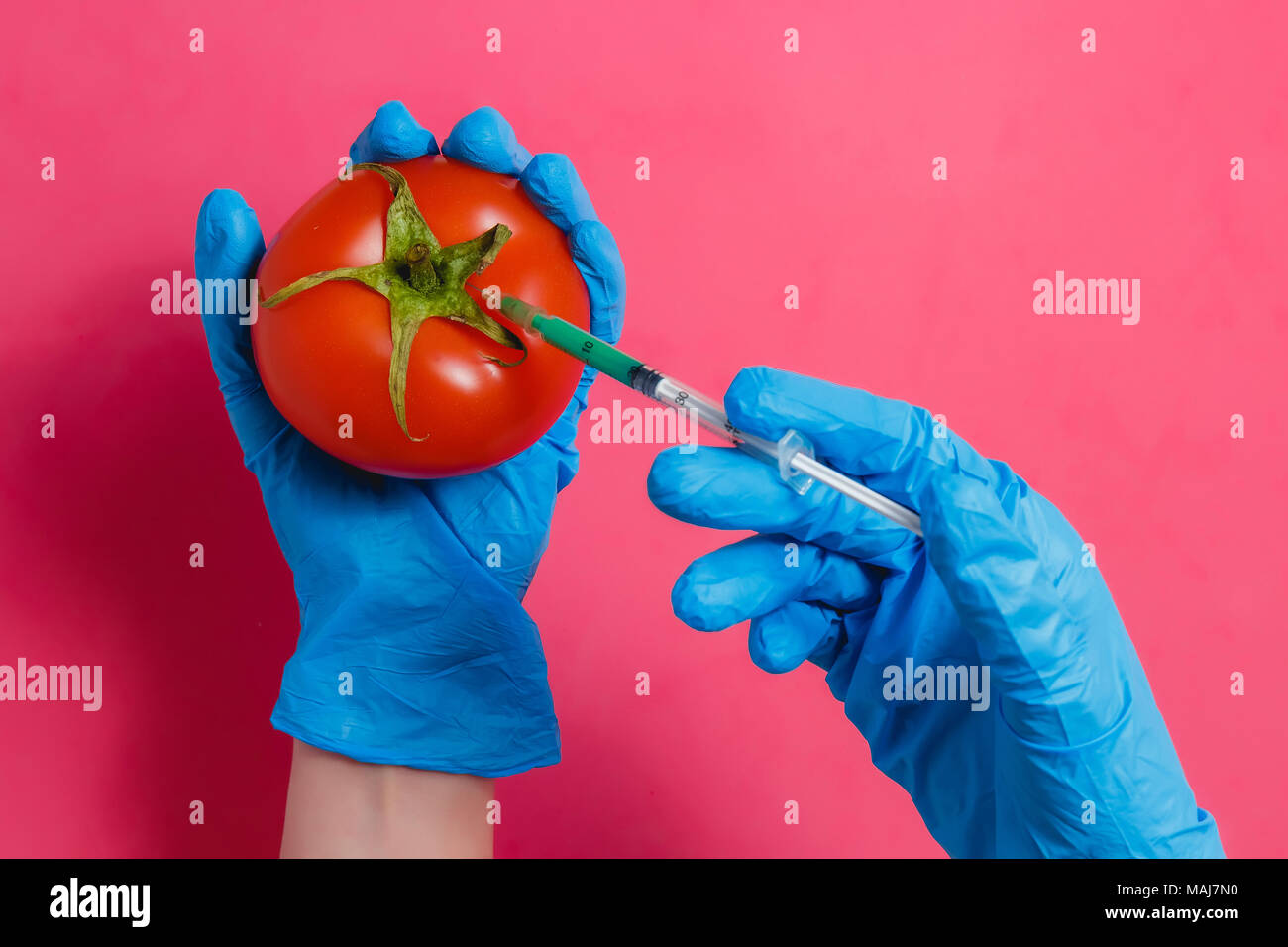 L'injection de liquide vert scientifique OGM à partir de la seringue dans la tomate rouge - Genetically Modified Food Concept. Banque D'Images