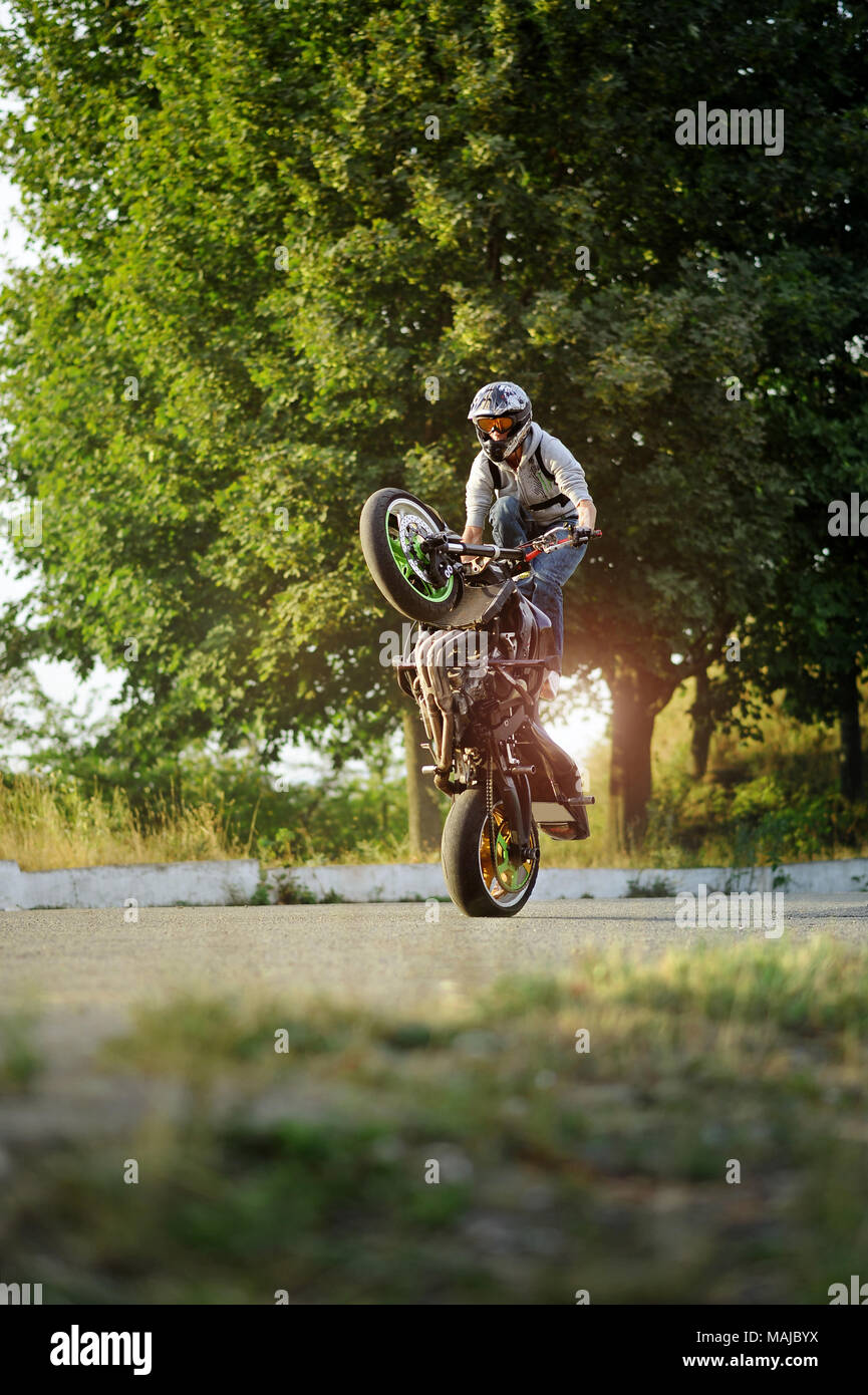 Kiev, Ukraine - 28 août 2015 : les jeunes biker est impressionnant avec ses aptitudes de conduite extrême sur les rues d'été de la ville. Vert des arbres sur l'arrière-plan. Le port de casque. Banque D'Images