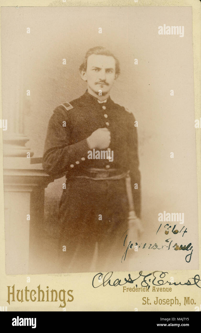 Près de portrait en pied de Charles F. Ernst en uniforme, et debout avec le coude gauche reposant sur un pilier et sa main gauche à l'intérieur de sa veste uniforme. 1864 'Yours Truly Chas. F. Ernst" (écrit sous l'image). 'Hutchings' et 'Frederick Avenue St.' (imprimé ci-dessous l'image). Titre : Charles F. Ernst, Commandant, 12e de cavalerie du Missouri (Union européenne). . 1864. Hutchings, Saint Joseph, Missouri Banque D'Images