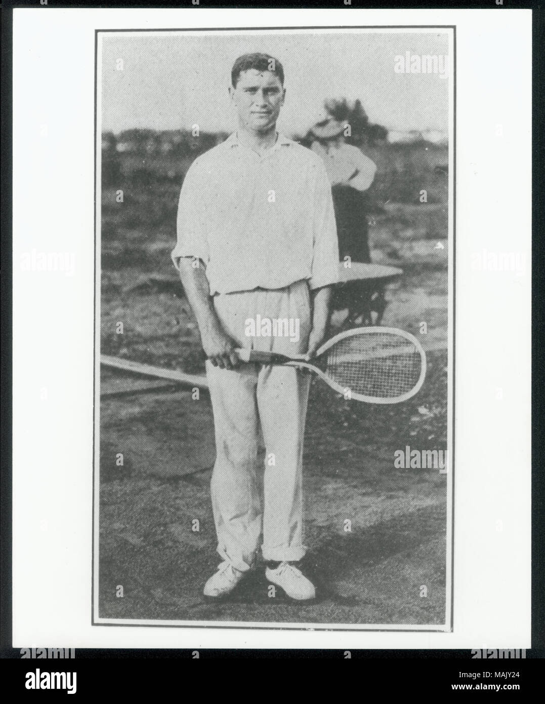 L'homme vêtu de blanc à manches longues, pantalon, chaussures et à l'extérieur debout tenant une raquette de tennis. Deux femmes se tenant debout en arrière-plan. Titre : Edgar W. Leonard, men's doubles et simples à la championne de tennis aux Jeux Olympiques de 1904. . 1904. Banque D'Images