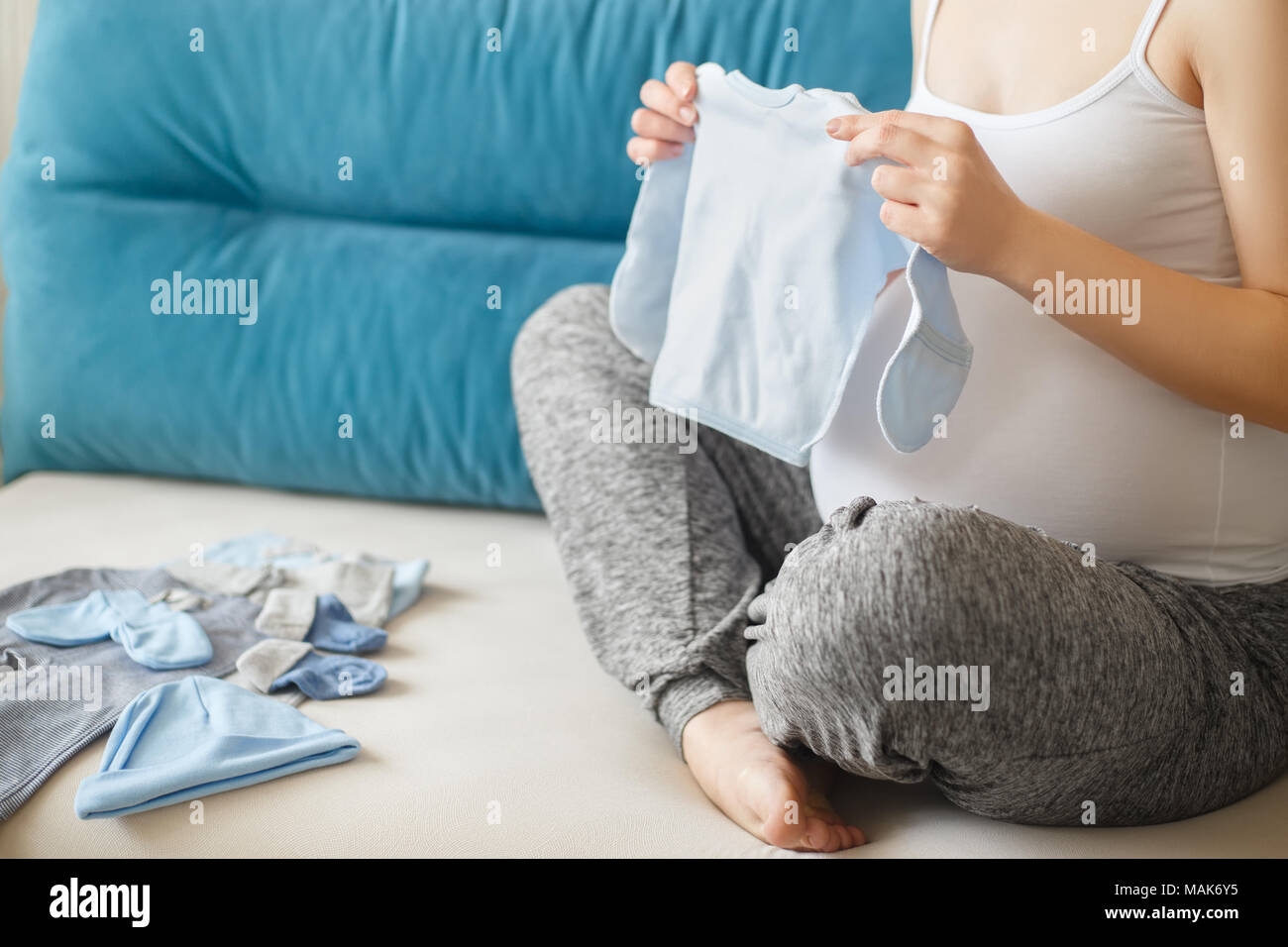 Femme enceinte libre de préparer les vêtements de bébé. Future maman, avec des vêtements pour nouveau-né. La grossesse, les gens, l'attente de bébé concept Banque D'Images