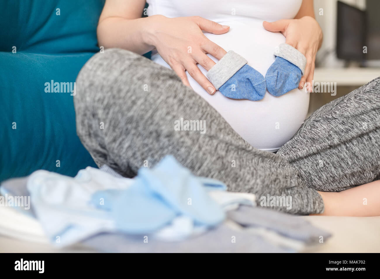 Pregnant woman holding chaussettes bleues sur son ventre. Future maman, préparer les vêtements de bébé. La grossesse, les gens, l'attente de bébé garçon concept Banque D'Images