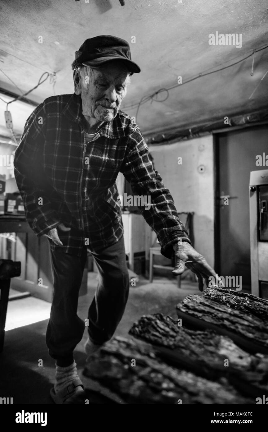 80 plus beaux ans senior man portrait. Noir et blanc de l'image complète du corps d'un homme âgé dans la chaufferie, fixant le feu à la maison de la chaleur. Banque D'Images