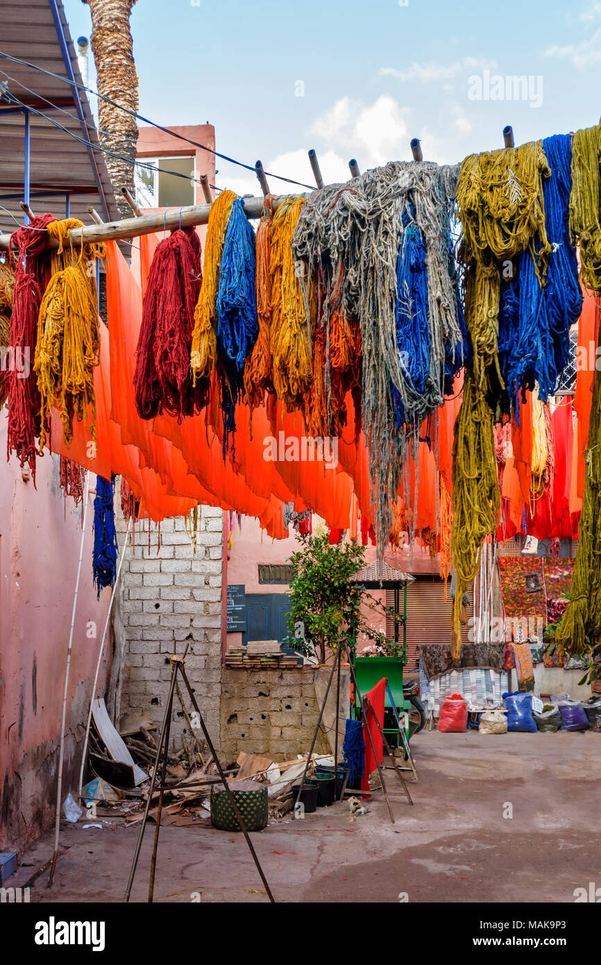 Place JEMAA EL FNA MARRAKECH MAROC Souk Médina écheveaux de laine et de tissus en laine teints multicolores suspendus à des poteaux et le séchage au soleil Banque D'Images