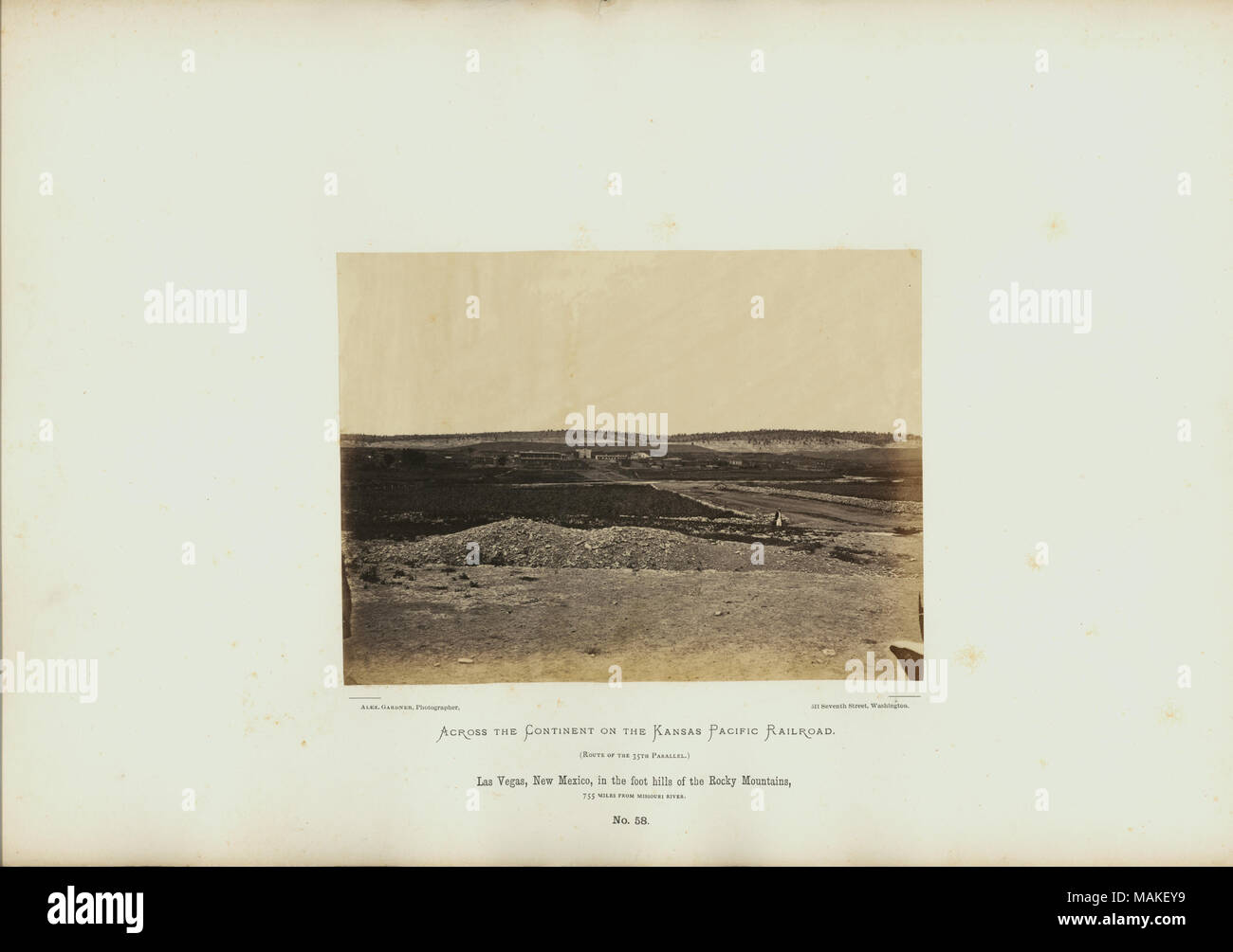 Las Vegas, Nouveau Mexique, dans les collines au pied des montagnes Rocheuses, 755 milles à partir de la rivière Missouri. Vue éloignée de la petite colonie entre faible, des collines rocheuses. Homme solitaire marche sur l'avant-plan à la mi-chemin. Titre : 'Las Vegas, Nouveau Mexique, dans les collines au pied des montagnes Rocheuses, 755 kilomètres de rivière Missouri." 58 de la plaque. . 1868. Alexander Gardner Banque D'Images