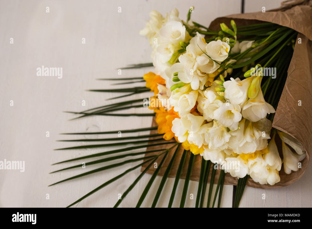 Bouquet de fleurs de freesia blanc et jaune enveloppé dans du papier craft  blanc pose sur table. Copier l'espace Photo Stock - Alamy