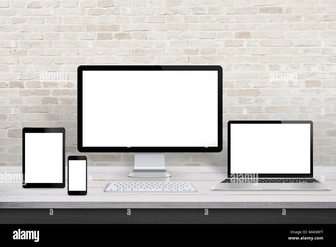 Plusieurs périphériques d'affichage pour la promotion de responsive web design. Bureau moderne bureau avec mur de brique en arrière-plan. Banque D'Images