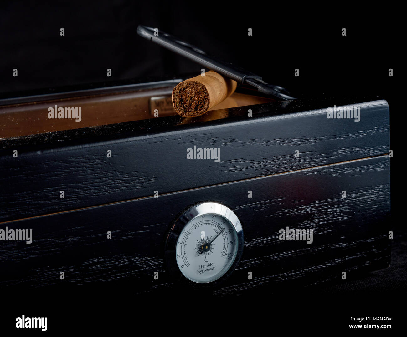 Une riche odeur de cigare, sur un humidor noire à côté d'un coupe-cigare tout droit. Fond noir Banque D'Images