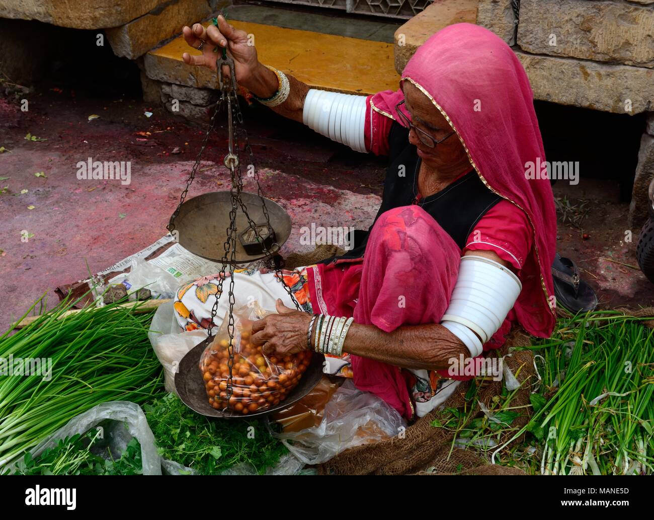 Personnes âgées femme indienne vend des fruits et légumes portant de nombreux bracelets blancs sur ses bras pour encourager la vie de son mari l'Inde Jaisalmer Banque D'Images