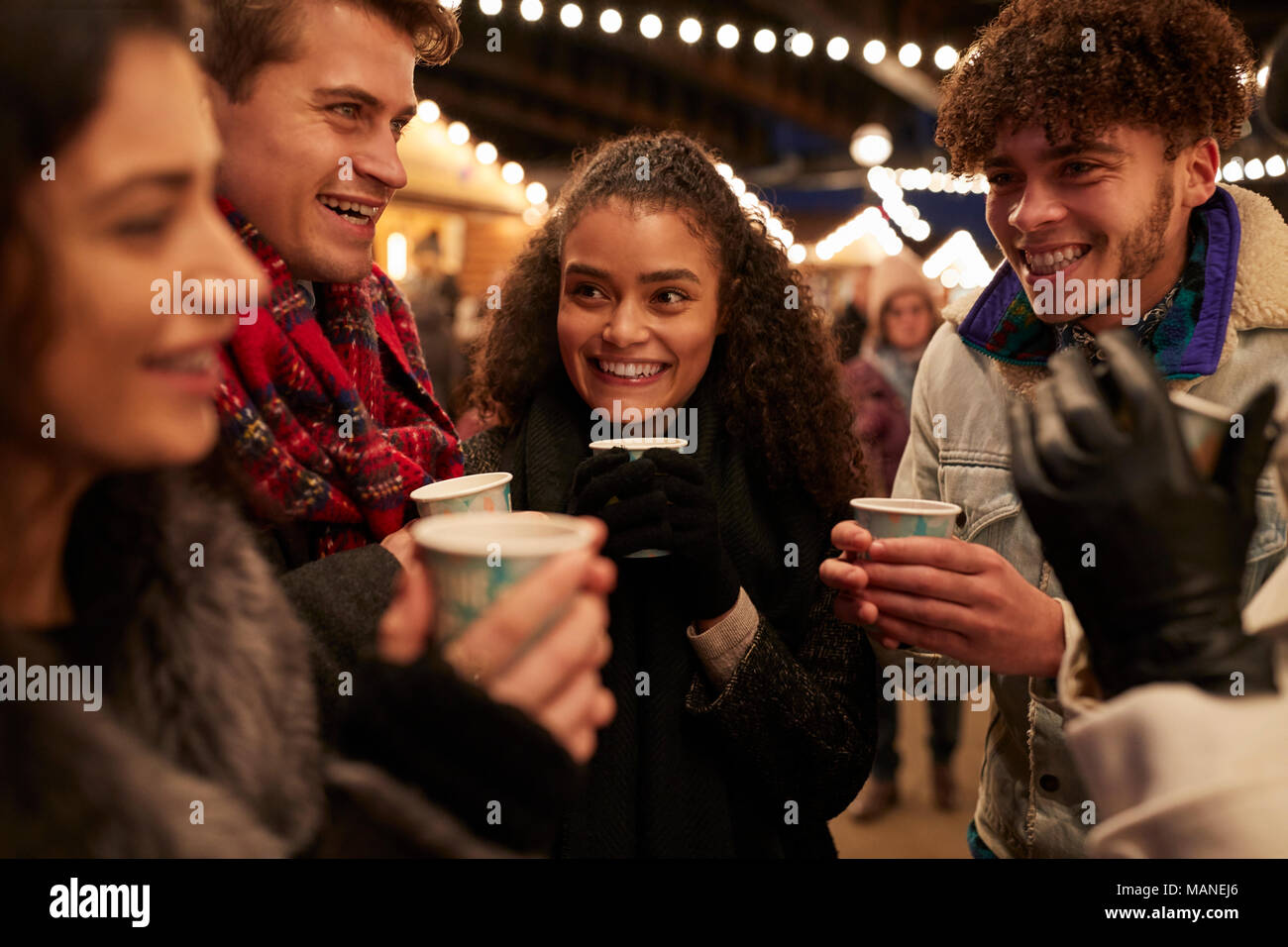 Groupe d'Amis de boire du vin chaud au marché de Noël Banque D'Images