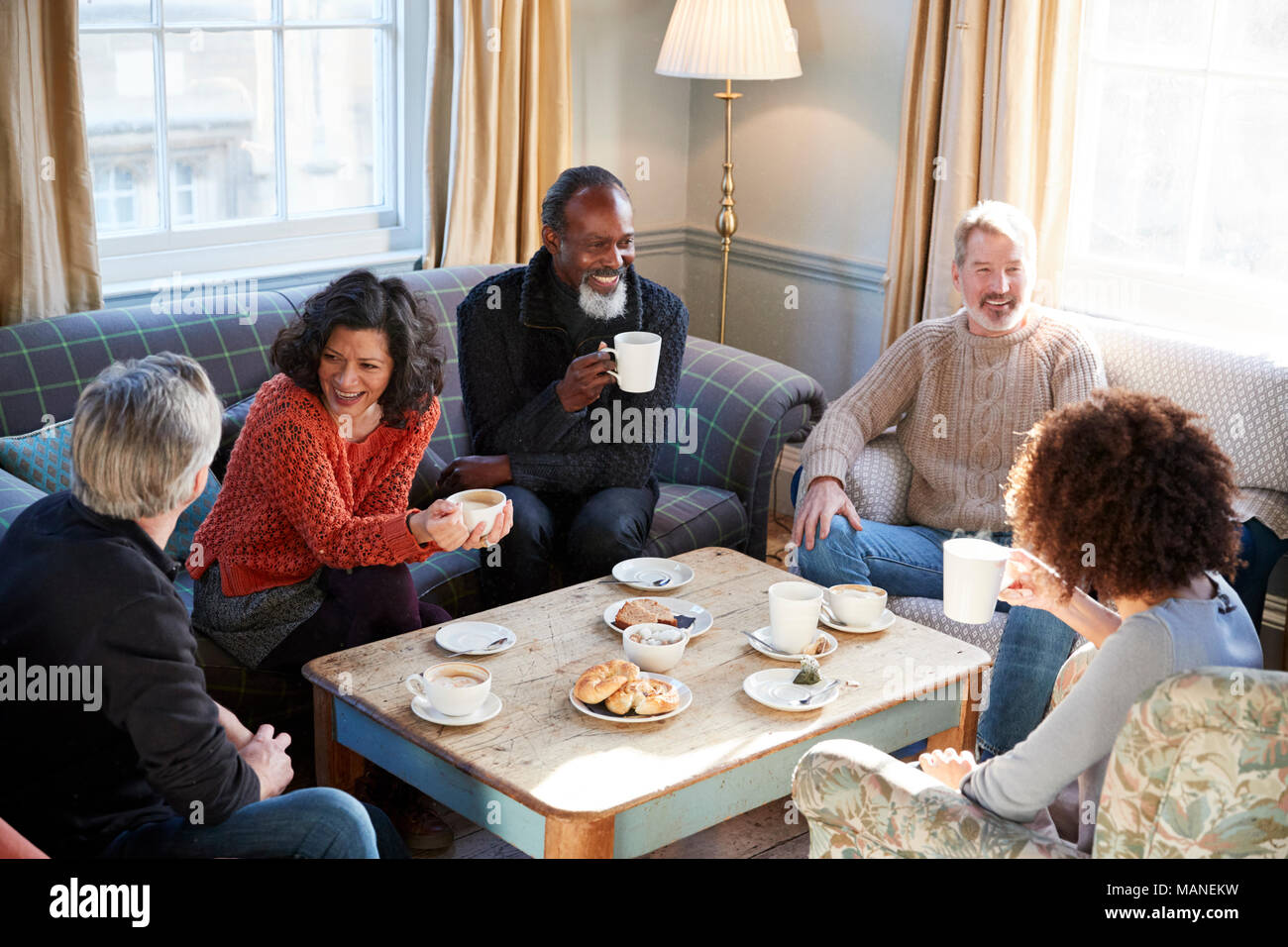 Groupe d'amis d'âge moyen autour de Réunion Table Dans Coffee Shop Banque D'Images