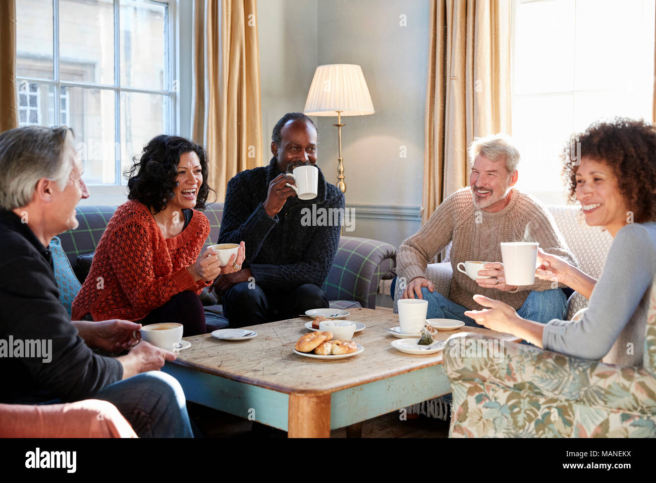 Groupe d'amis d'âge moyen autour de Réunion Table Dans Coffee Shop Banque D'Images