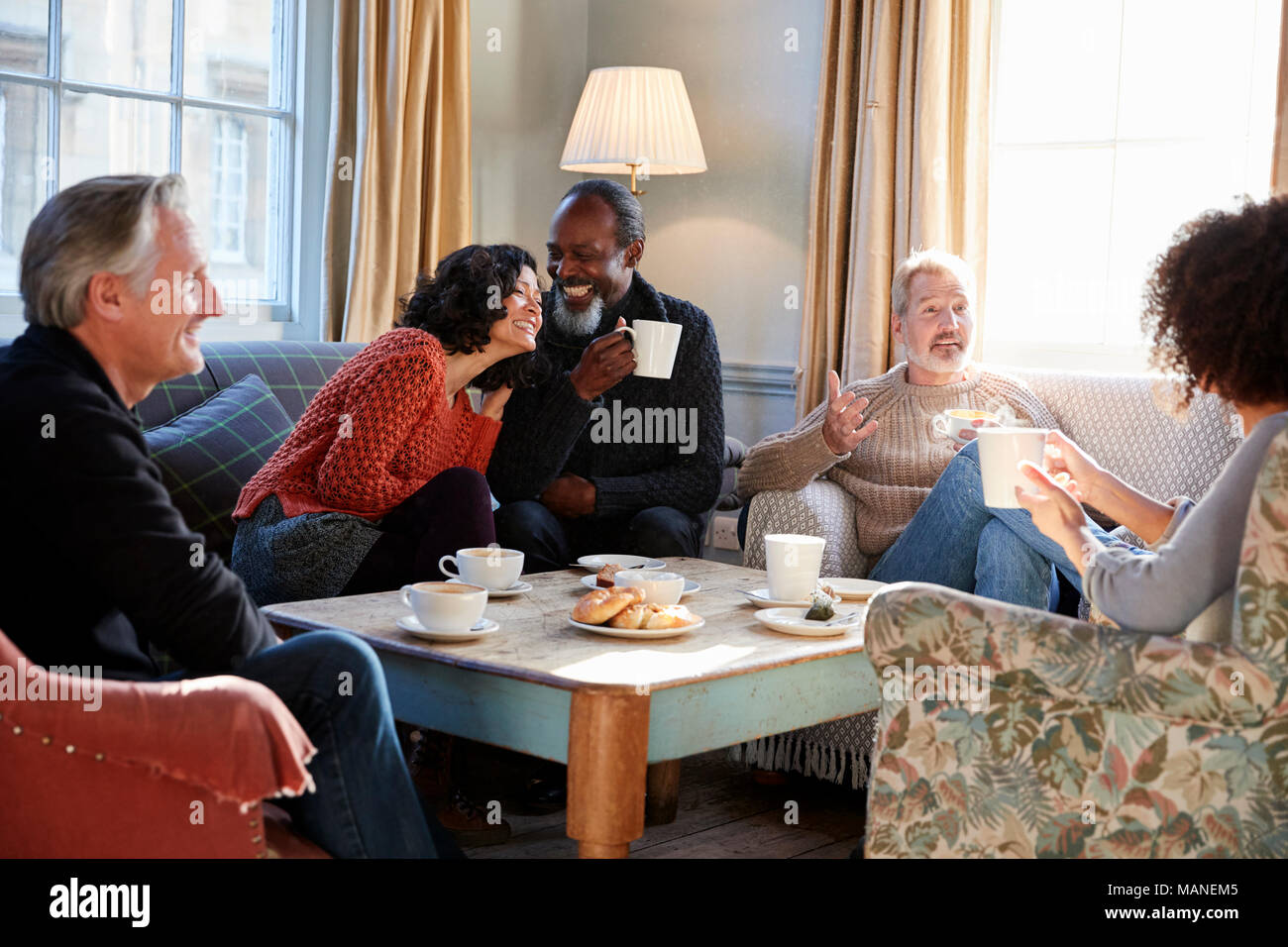 Groupe d'amis d'âge moyen autour de Réunion Table Dans Coffee Shop Banque D'Images