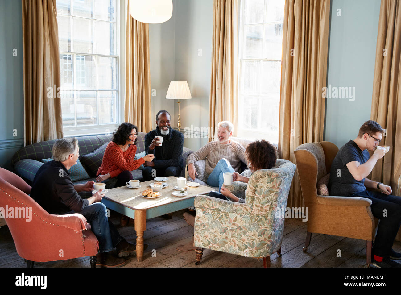 Groupe d'amis d'âge moyen autour de Réunion Table Dans Coffee Shop Banque D'Images