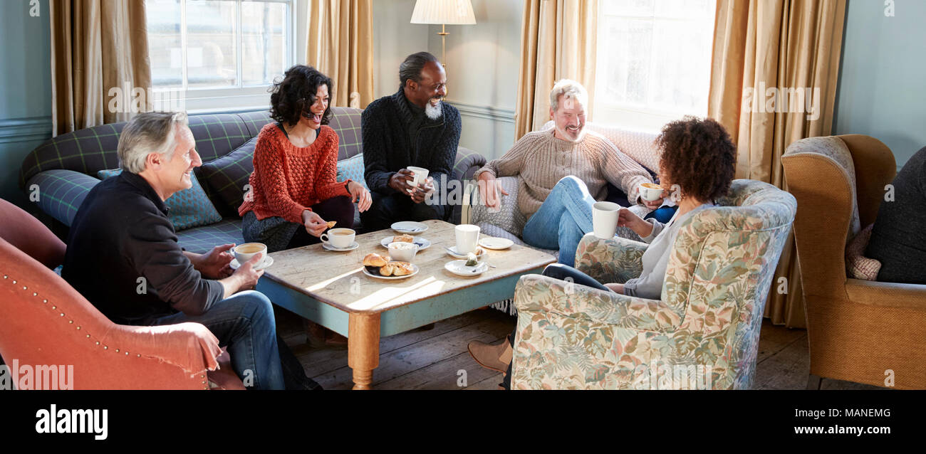 Groupe d'amis d'âge moyen autour de Réunion Table Dans Coffee Shop Banque D'Images
