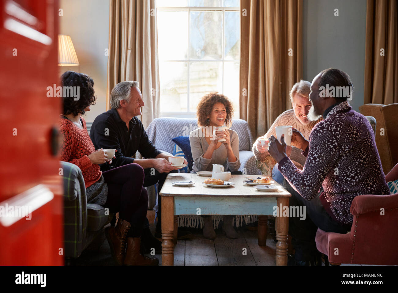 Groupe d'amis d'âge moyen autour de Réunion Table Dans Coffee Shop Banque D'Images