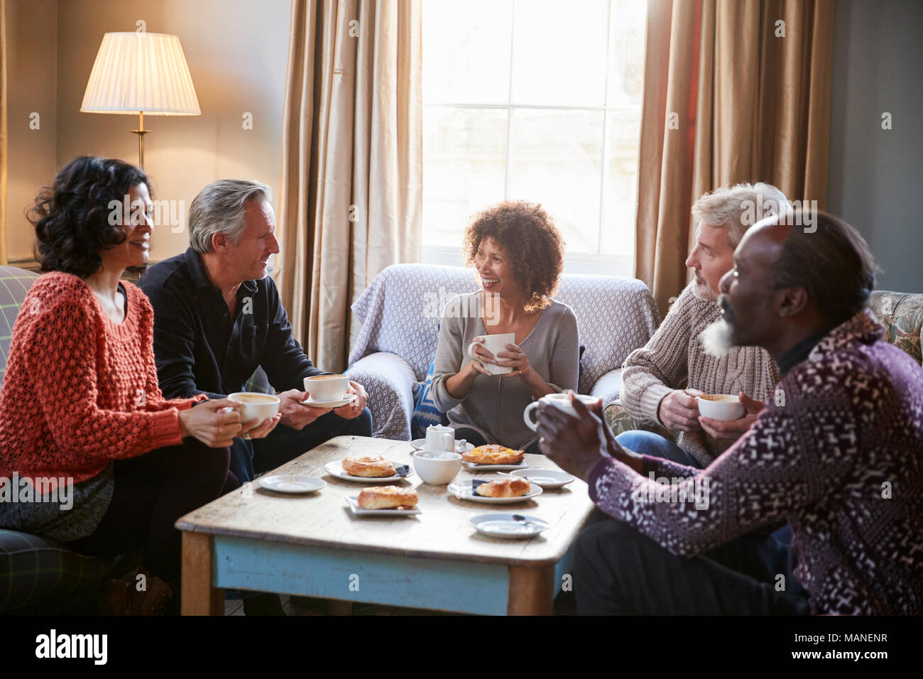 Groupe d'amis d'âge moyen autour de Réunion Table Dans Coffee Shop Banque D'Images