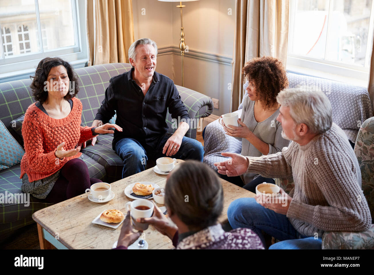 Groupe d'amis d'âge moyen autour de Réunion Table Dans Coffee Shop Banque D'Images