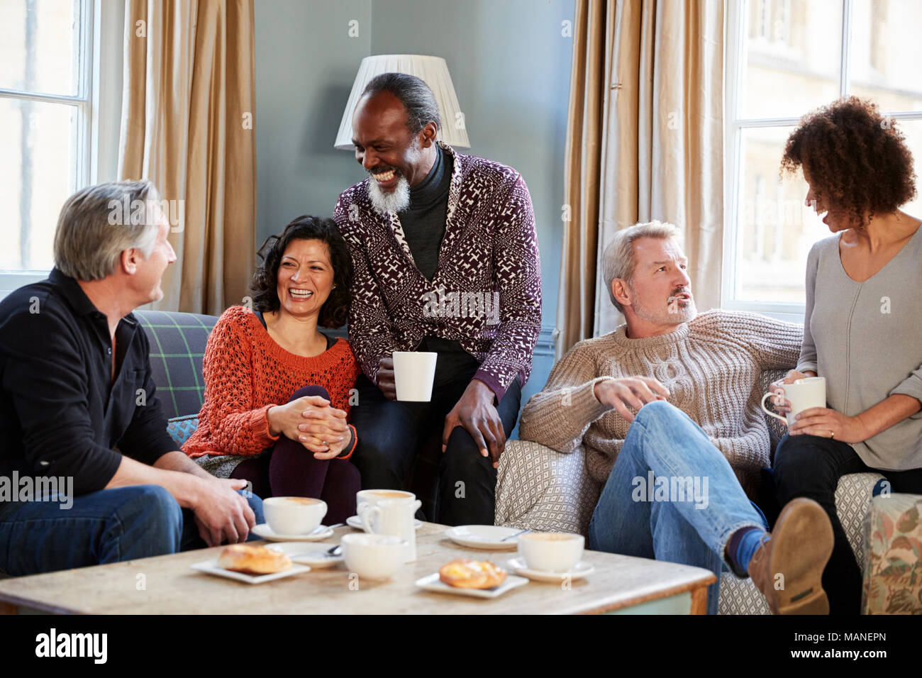 Groupe d'amis d'âge moyen autour de Réunion Table Dans Coffee Shop Banque D'Images
