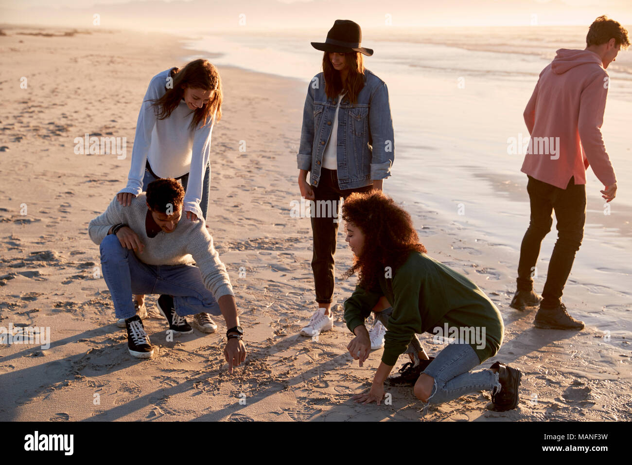 Amis jouant et des zéros traverse dans le sable sur la plage d'hiver Banque D'Images
