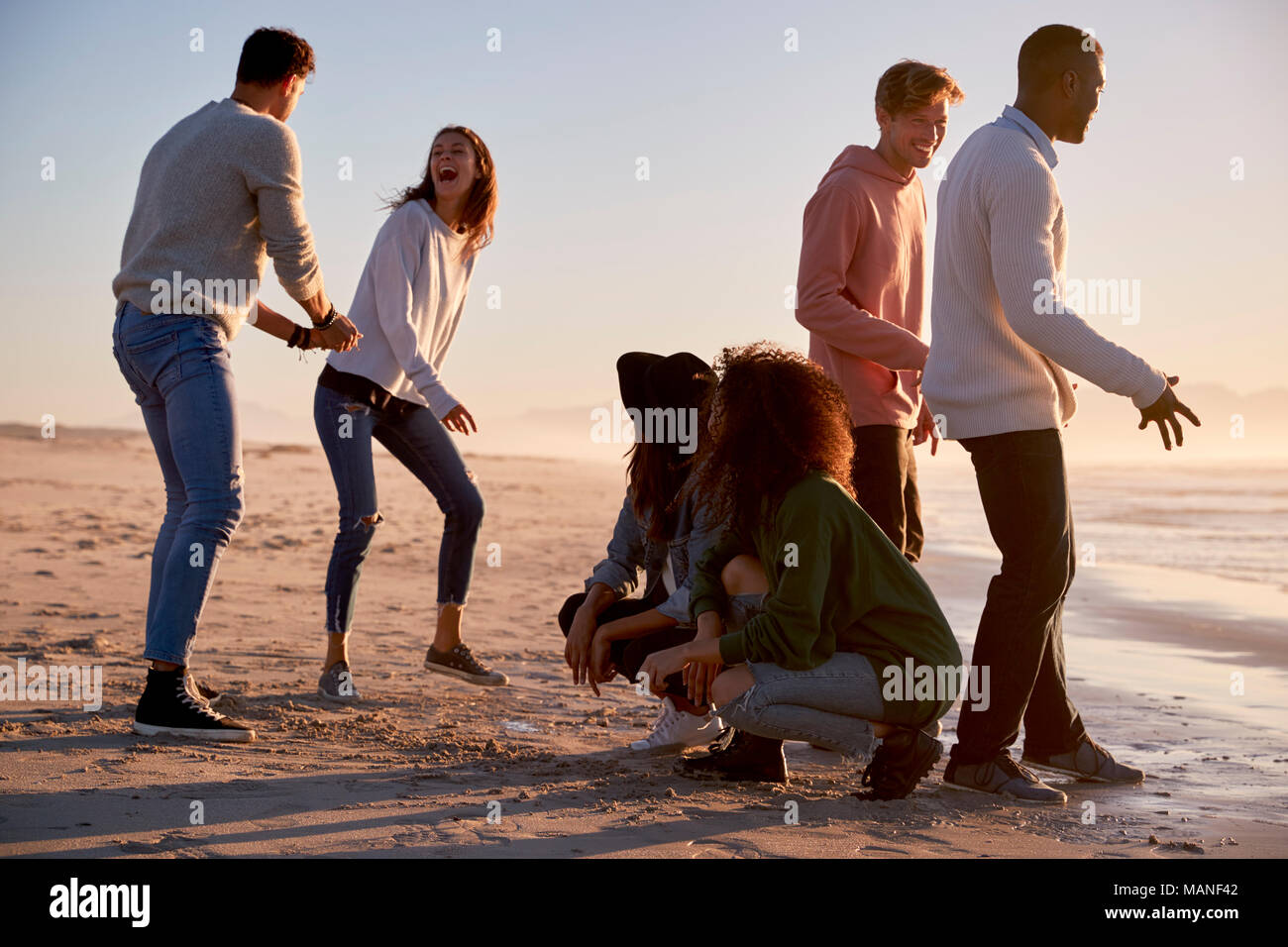 Amis jouant et des zéros traverse dans le sable sur la plage d'hiver Banque D'Images