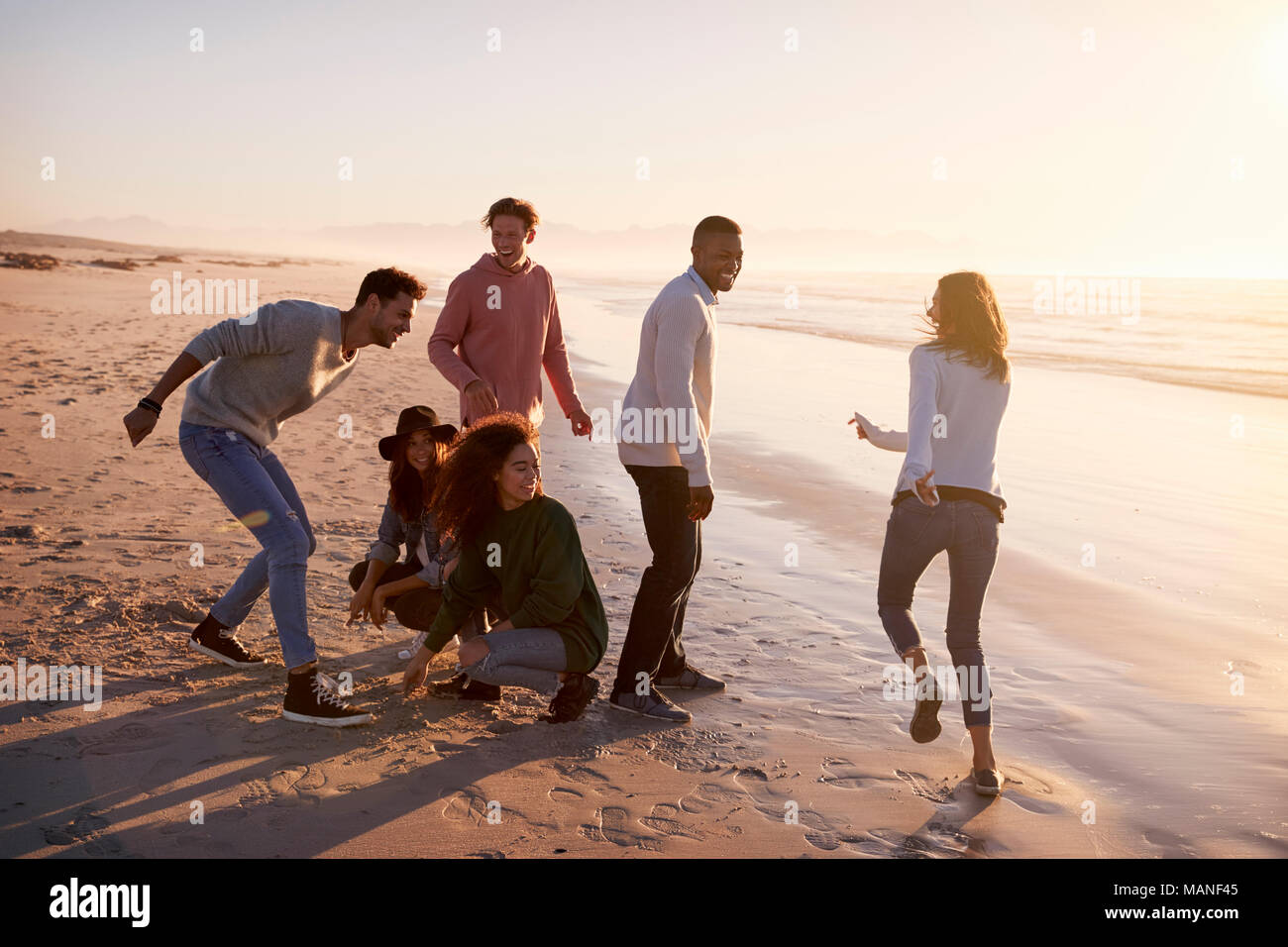 Amis jouant et des zéros traverse dans le sable sur la plage d'hiver Banque D'Images
