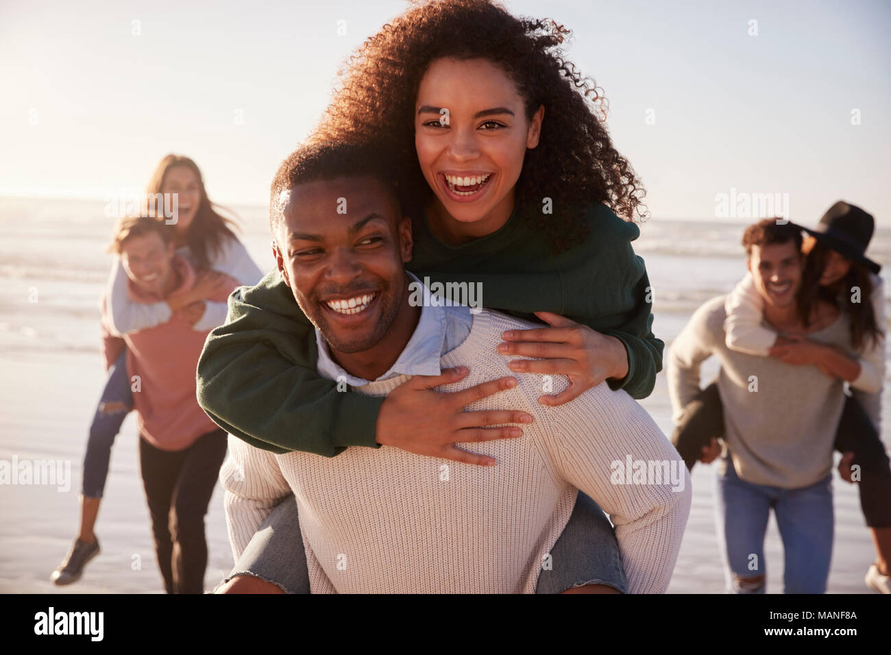Groupe d'amis ayant la race de ferroutage sur l'ensemble de la plage d'hiver Banque D'Images