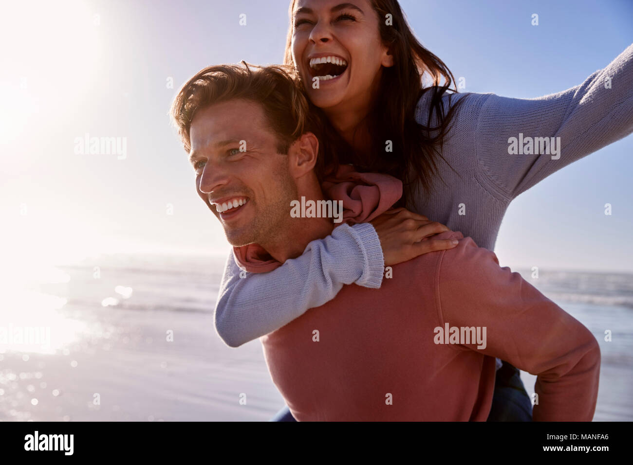 Man Giving Woman Piggyback sur Winter Beach Locations Banque D'Images