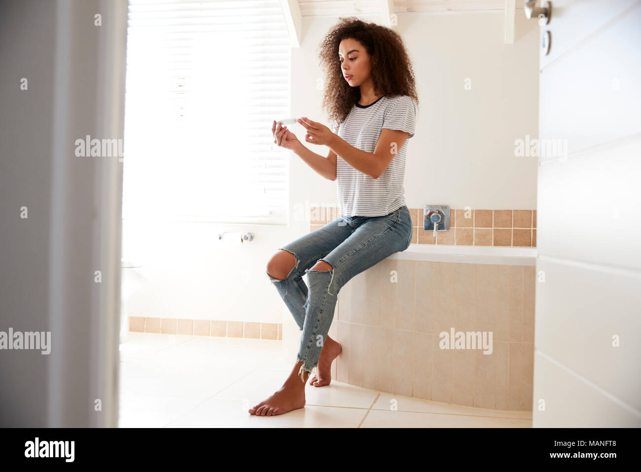 Femme dans la salle de bains avec concernés Test de grossesse à domicile Banque D'Images