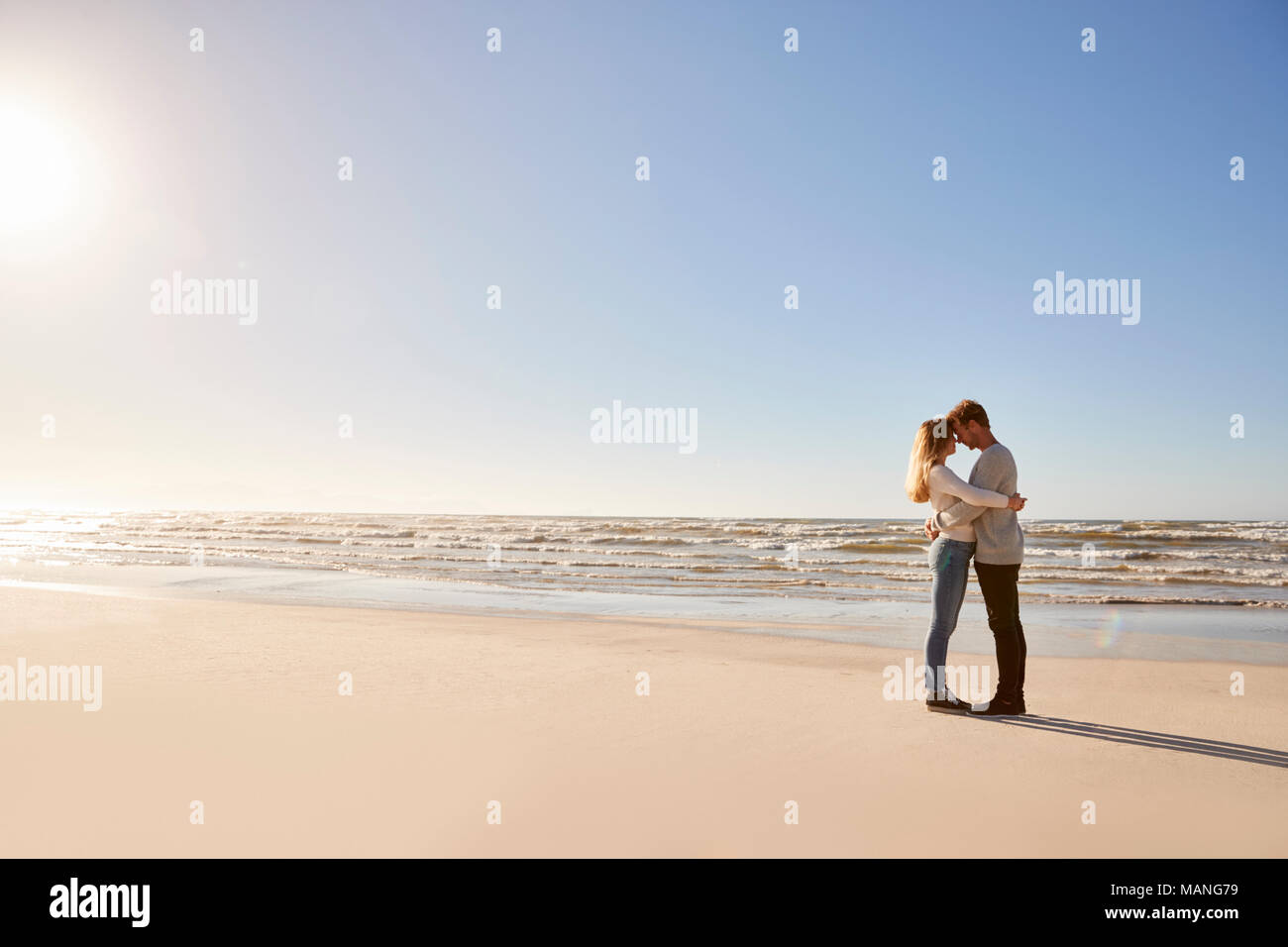 Hiver romantique Couple Embracing On Beach Banque D'Images