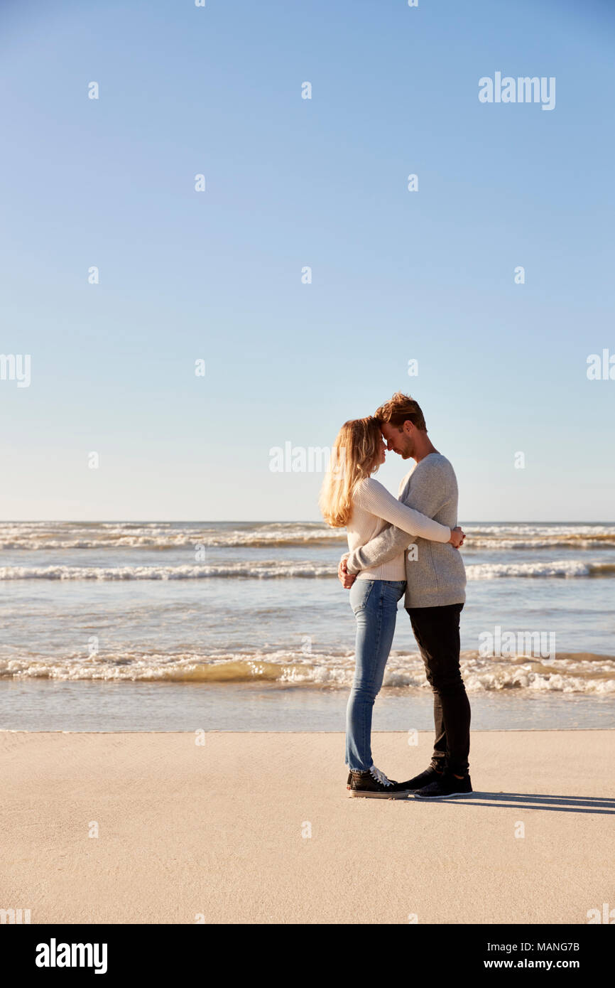 Hiver romantique Couple Embracing On Beach Banque D'Images