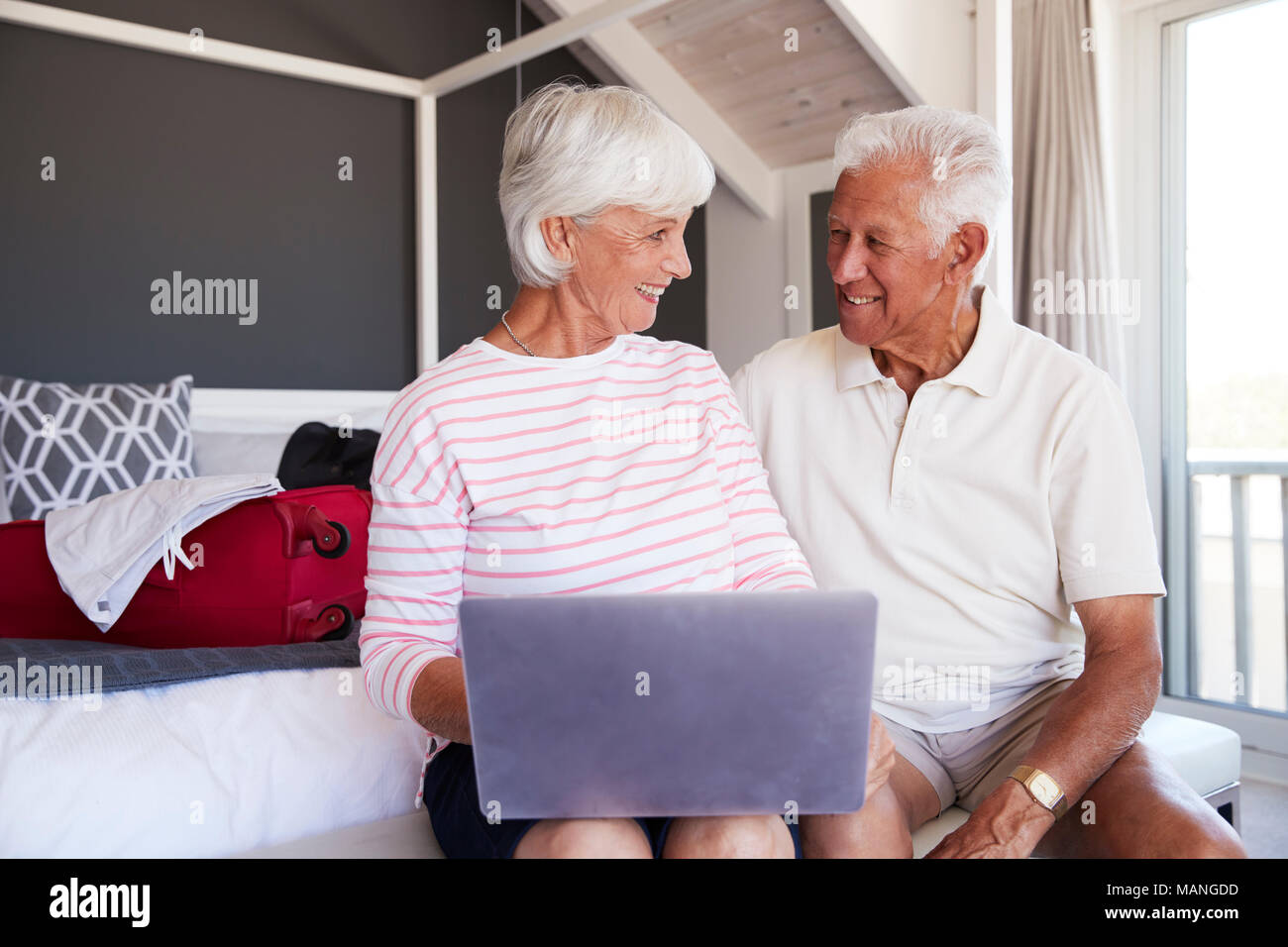 Senior Couple Regardez comme ils l'ordinateur portable à l'Hôtel de maison de vacances Banque D'Images