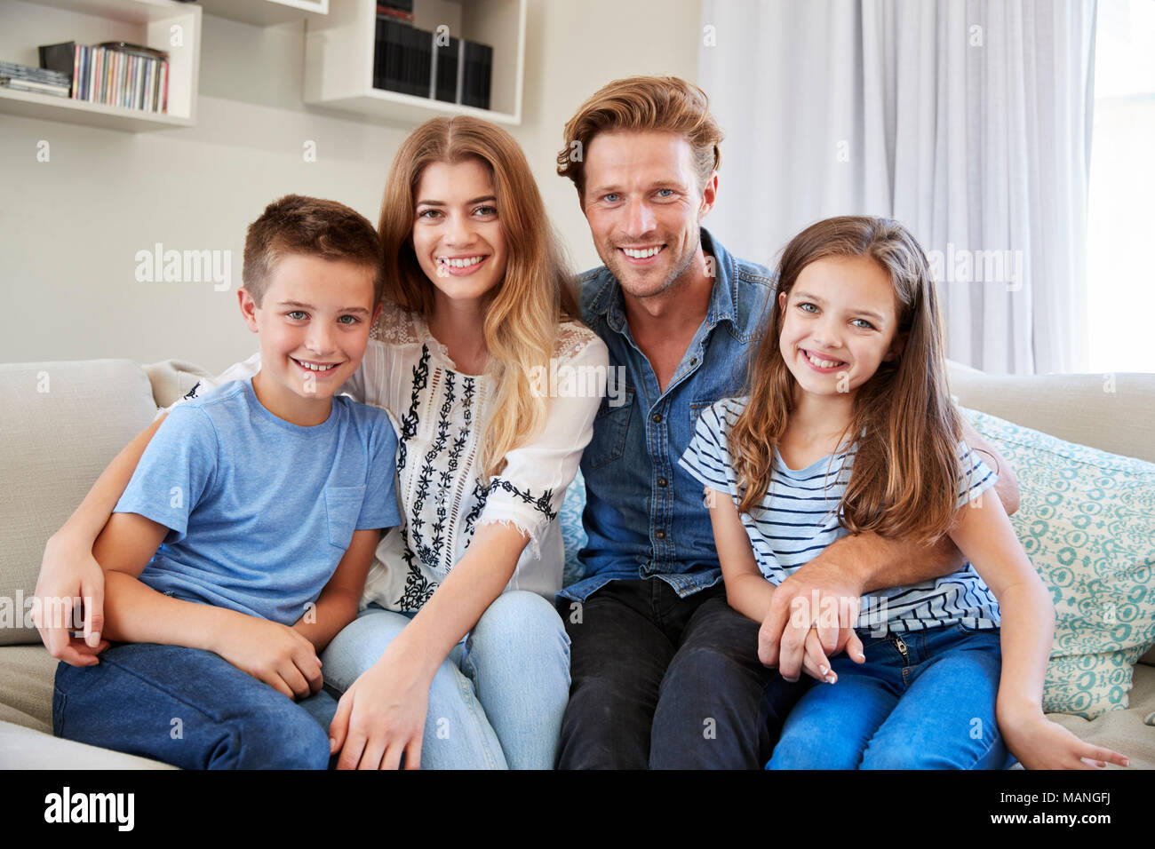 Portrait Of Smiling Family Sitting on Sofa At Home Together Banque D'Images