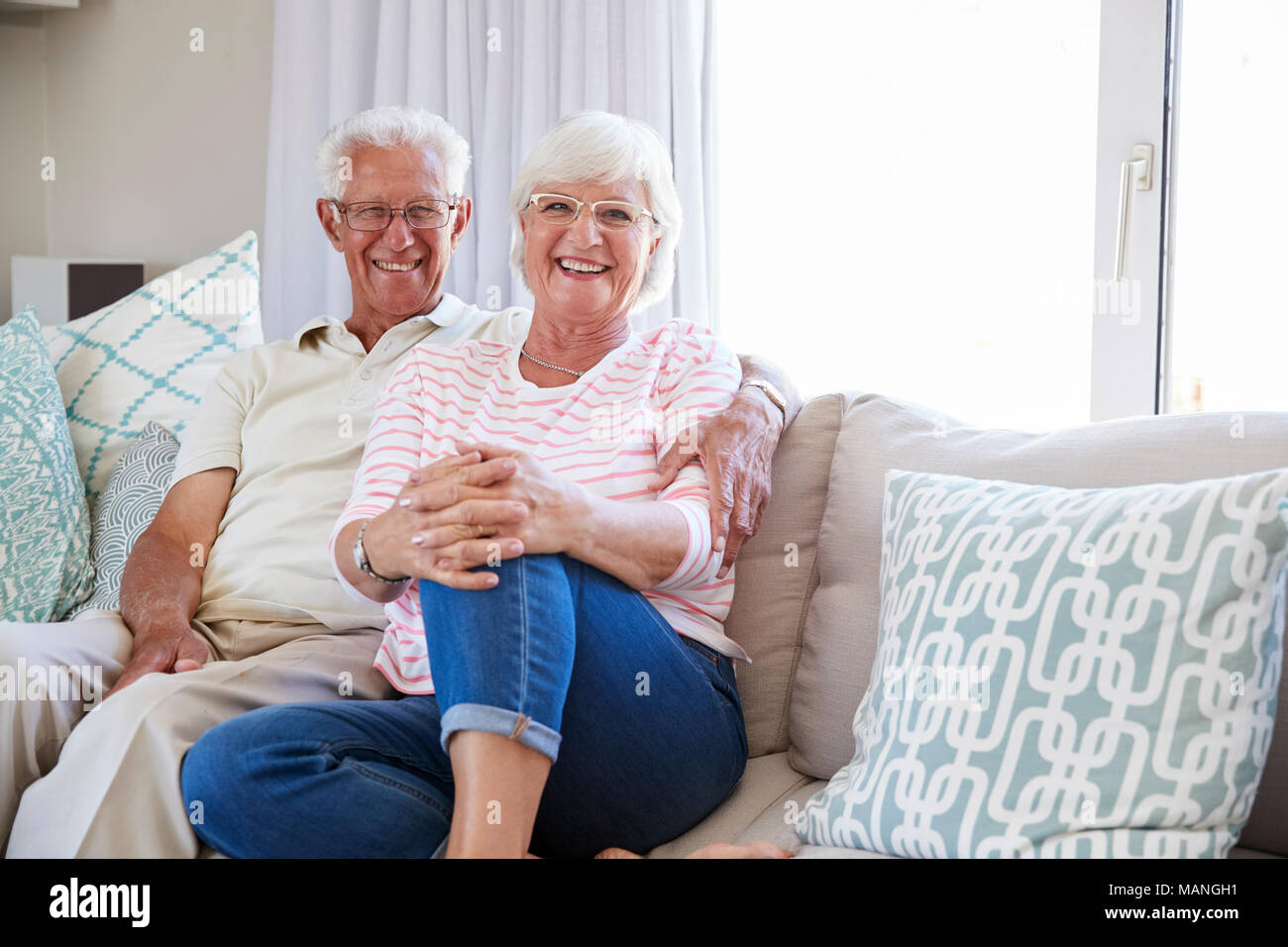 Portrait of Senior Couple Relaxing On Sofa At Home Together Banque D'Images