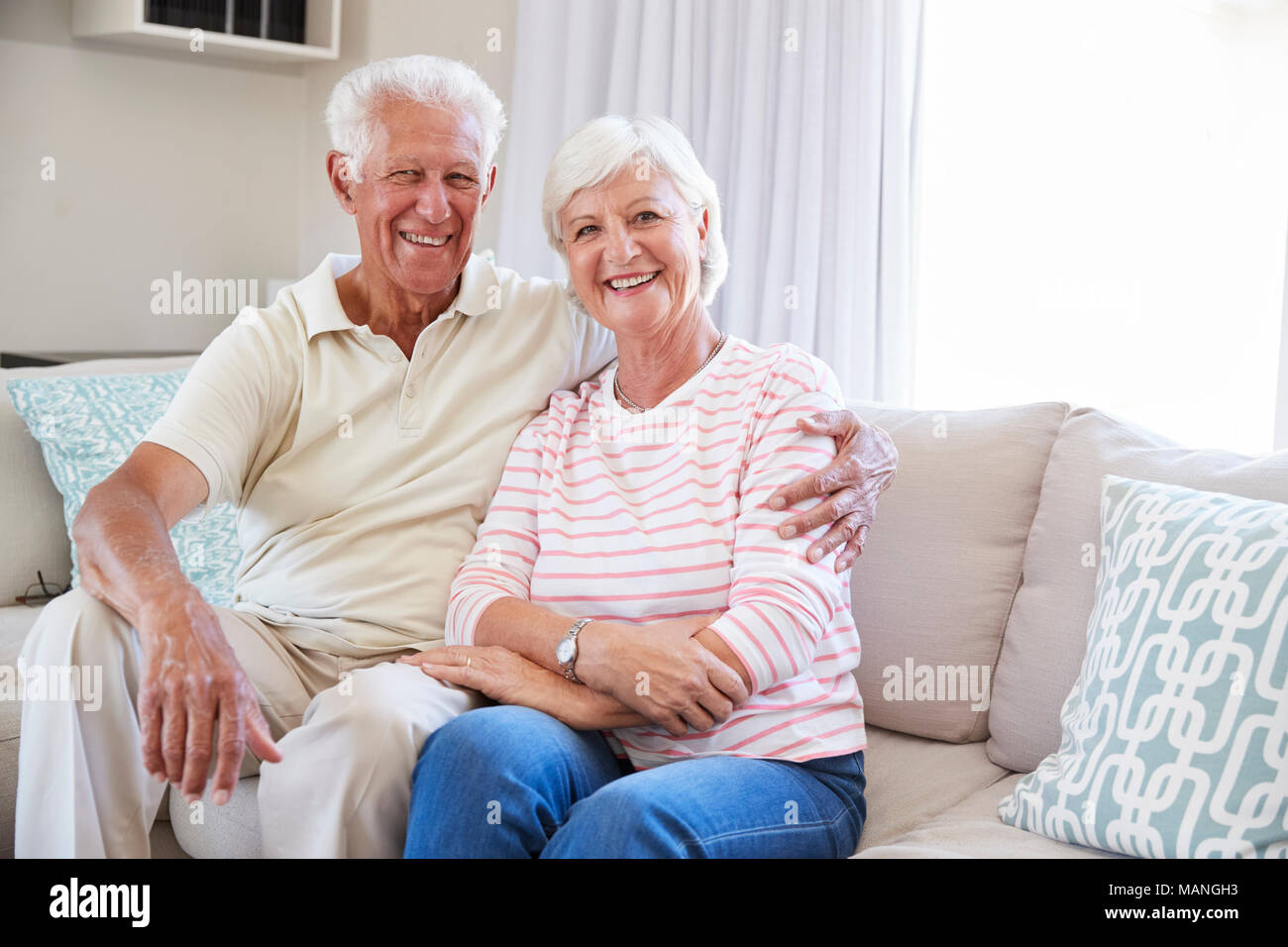 Portrait of Senior Couple Relaxing On Sofa At Home Together Banque D'Images