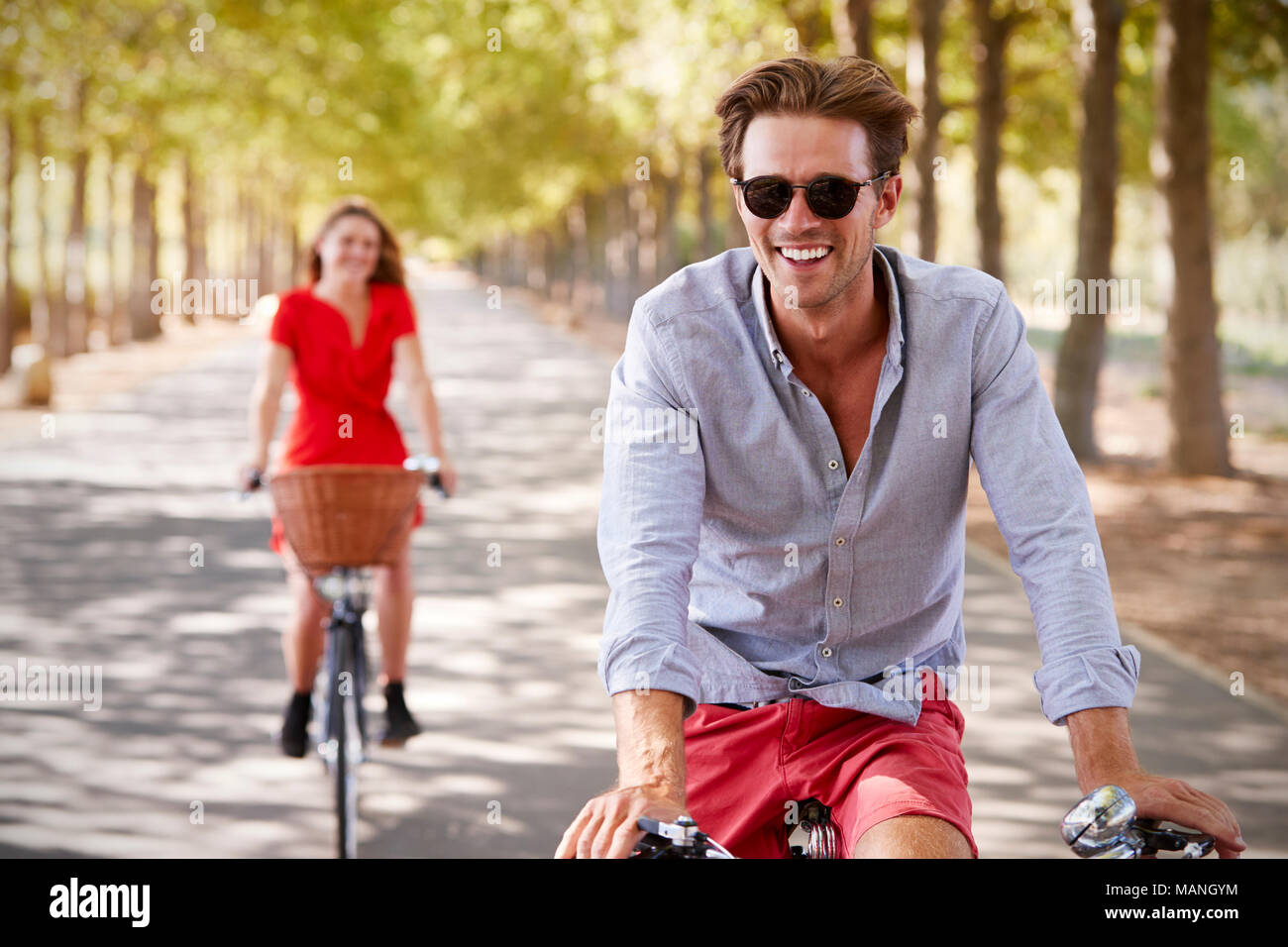 Les jeunes adultes blanc couple riding bikes sur une calme route ensoleillée Banque D'Images