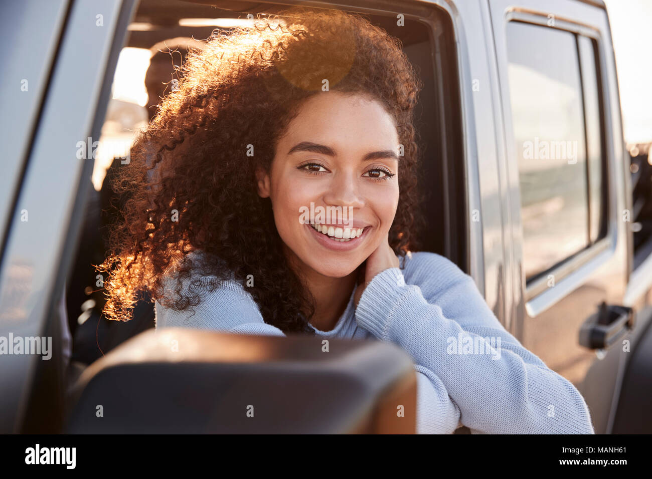 Jeune femme regardant par la fenêtre du passager avant d'une voiture Banque D'Images