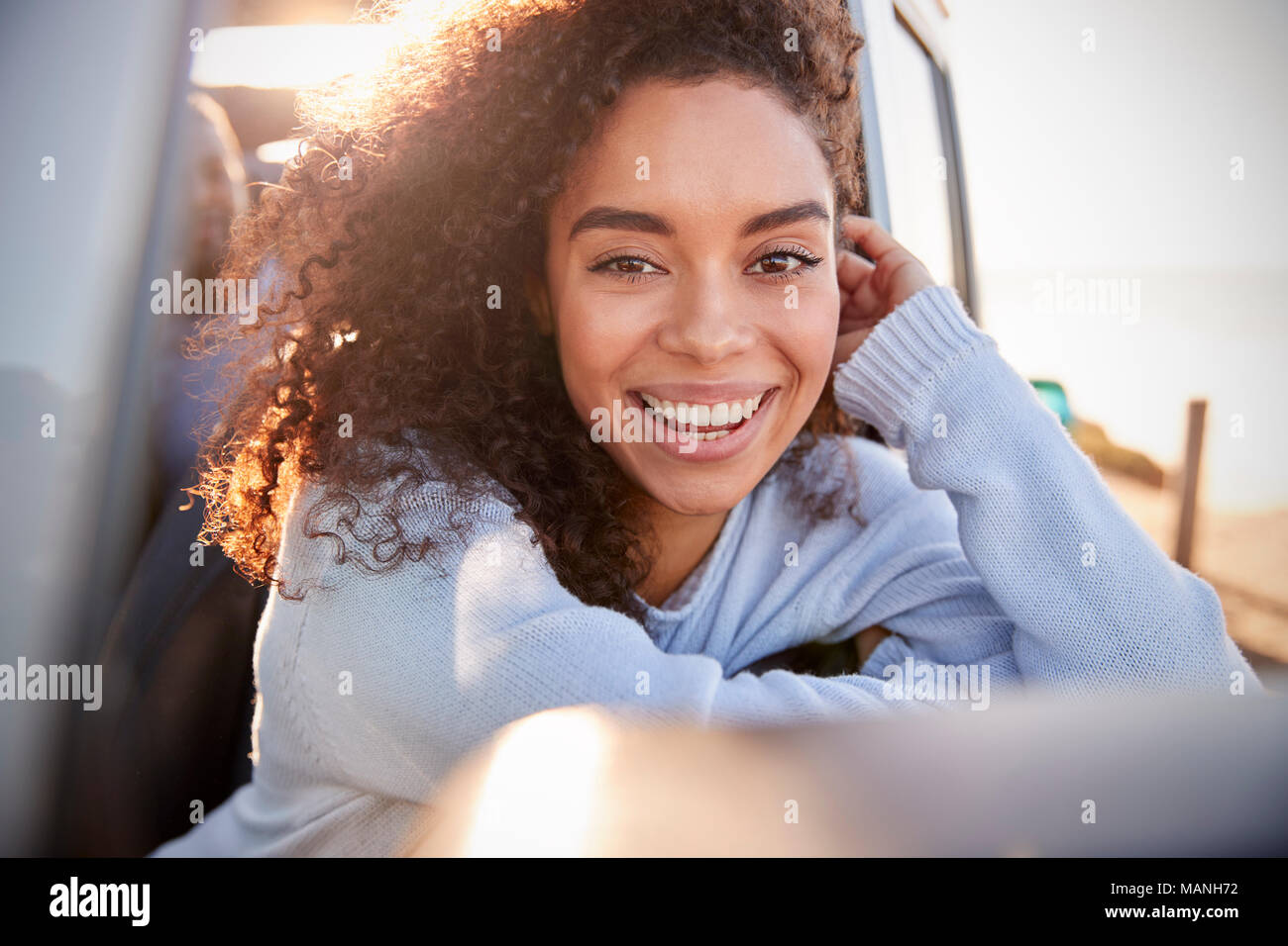 Young woman leaning on fenêtre ouverte de la voiture à la recherche à l'appareil photo Banque D'Images