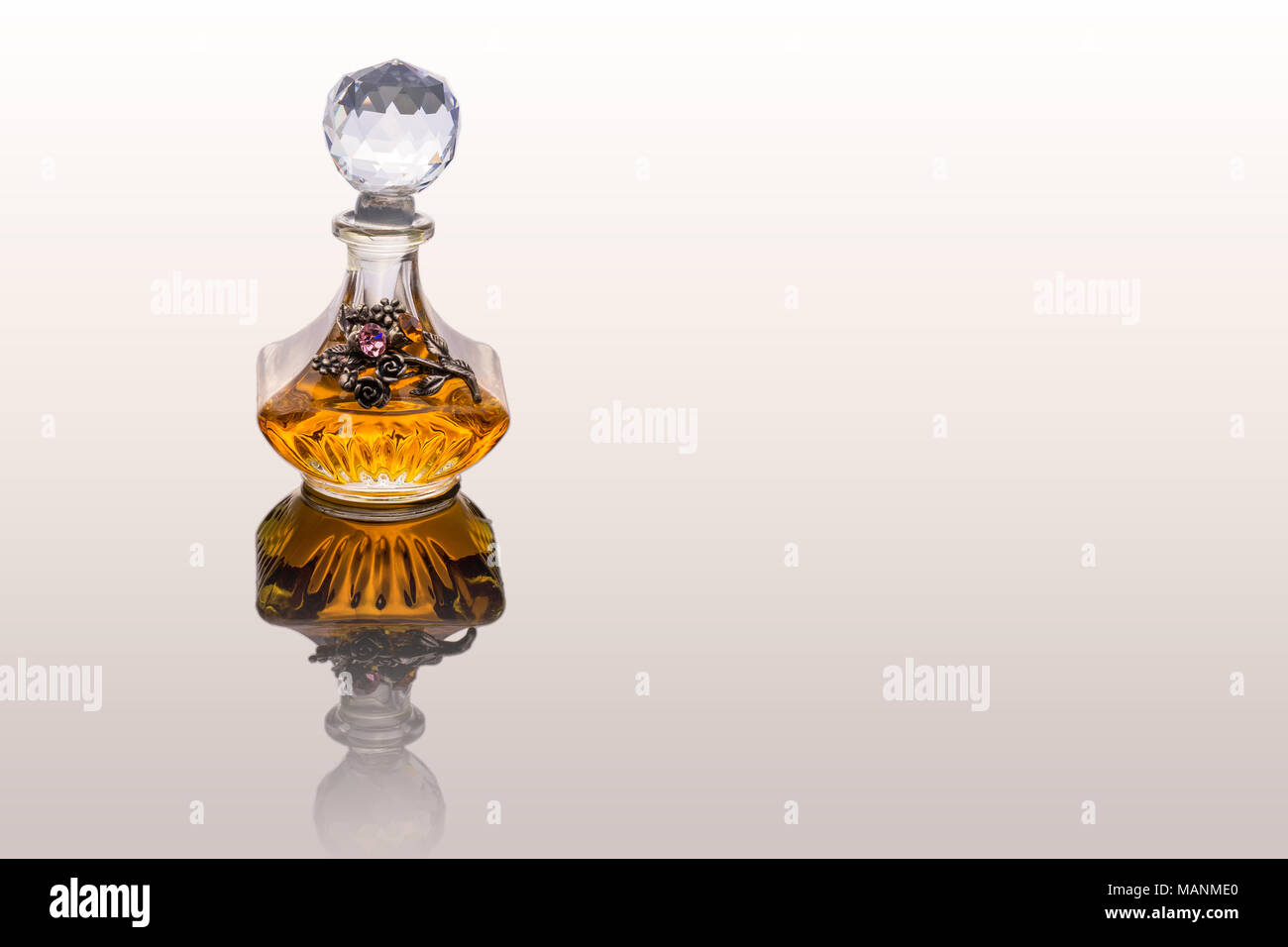 Gros plan de luxe traditionnel arabe Oud Parfum Huile d'orange dans un beau bol en verre de cristal clair fait main et bouteille compte-gouttes en verre isolé sur Banque D'Images