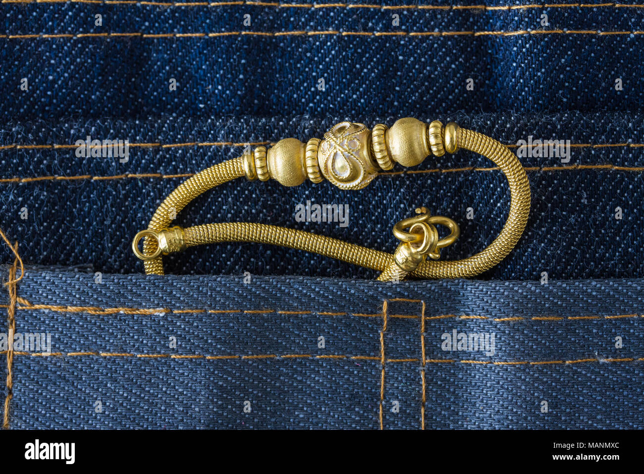 Bracelet en or sur un tissu de fond, jeans Banque D'Images