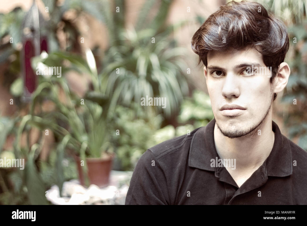 Portrait of a young man looking at camera, de réflexion et de sérieux, à l'extérieur. Banque D'Images