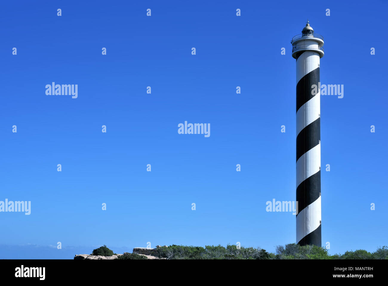 Gyrophare ou phare rayé sur l'île d'Ibiza. Phare noir et blanc sur une falaise côte ou côte. Banque D'Images