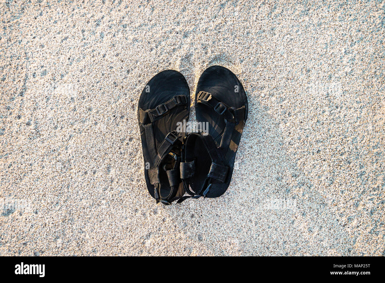 Men's sandales noires sur du sable blanc. tour en mer Banque D'Images