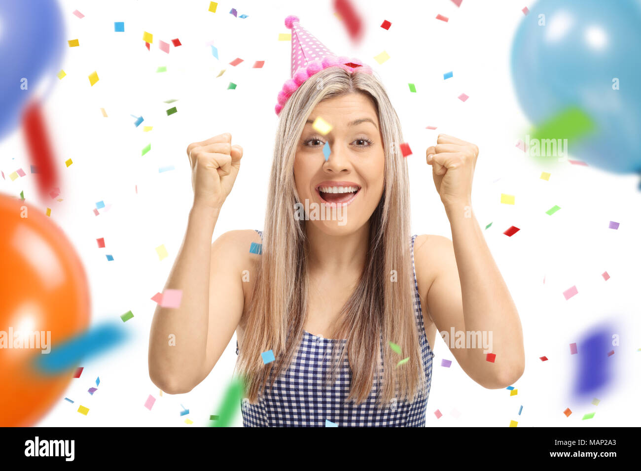 Jeune femme portant un chapeau de fête avec bonheur les gestes courants de confettis et de ballons voler autour d'elle isolé sur fond blanc Banque D'Images